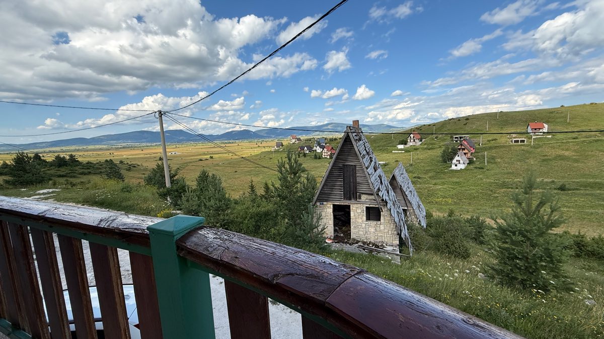Pogled s balkona na planinske kuće i polje